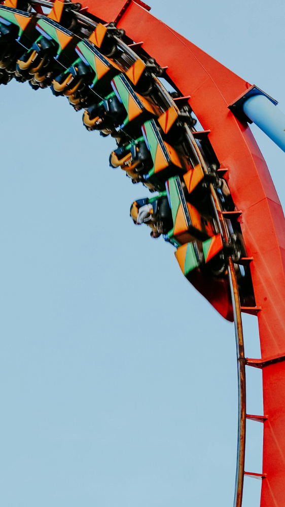 Roller coaster reaching the peak of a loop, with riders experiencing thrills at an amusement park, showcasing vibrant colors and excitement in the air.