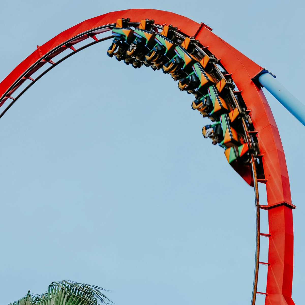 Roller coaster reaching the peak of a loop, with riders experiencing thrills at an amusement park, showcasing vibrant colors and excitement in the air.