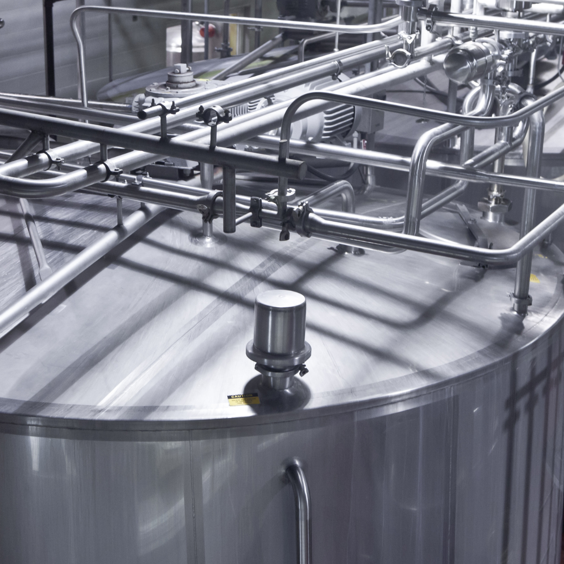Industrial chemical processing equipment featuring stainless steel tanks and piping systems, utilized in petrochemical manufacturing.