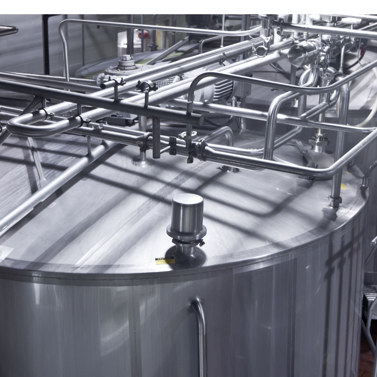 Industrial chemical processing equipment featuring stainless steel tanks and piping systems, utilized in petrochemical manufacturing.