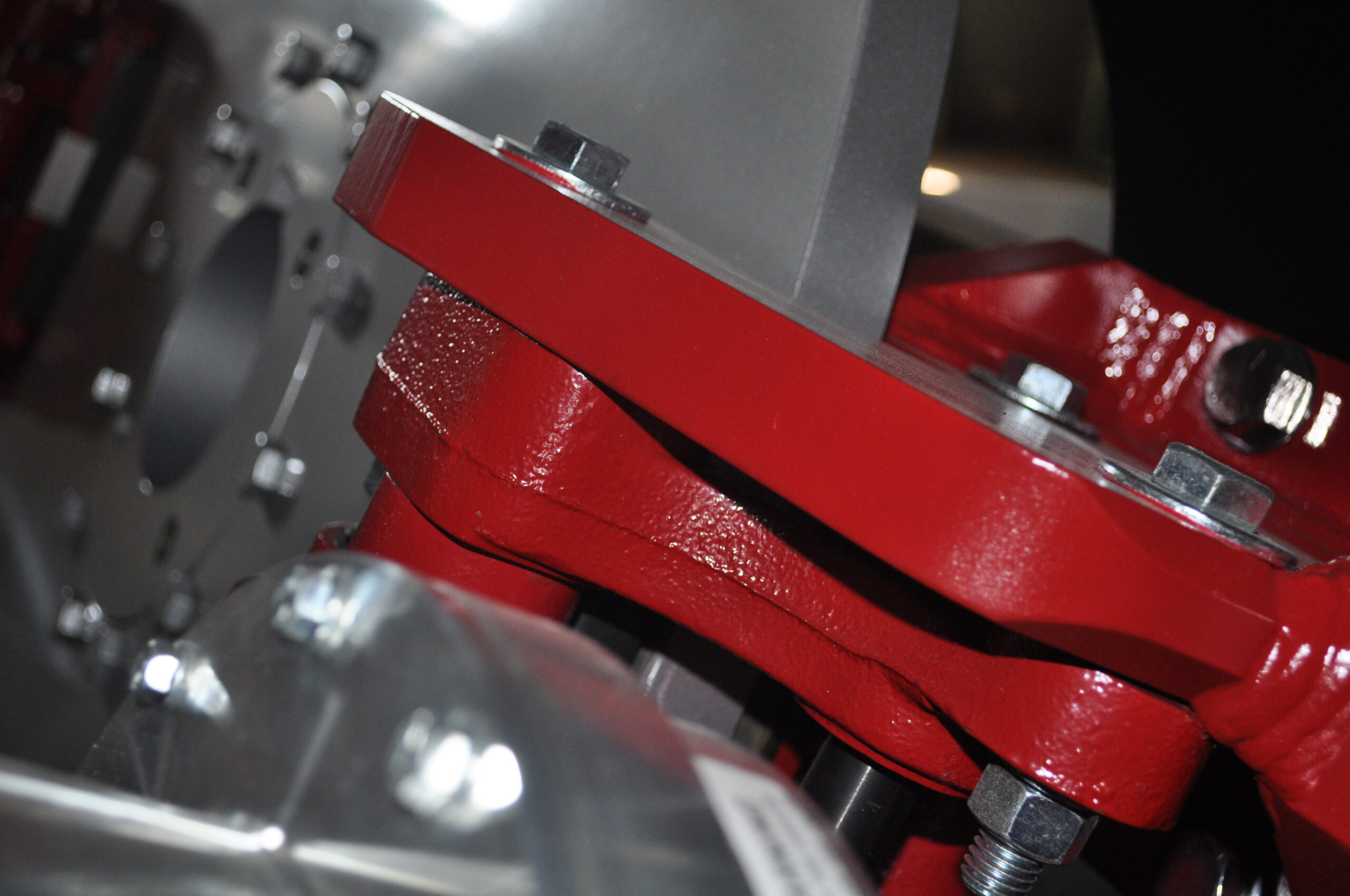 Close-up view of a red roller assembly in a rolling mill, showcasing detailed metal components and fasteners essential for metal processing machinery.