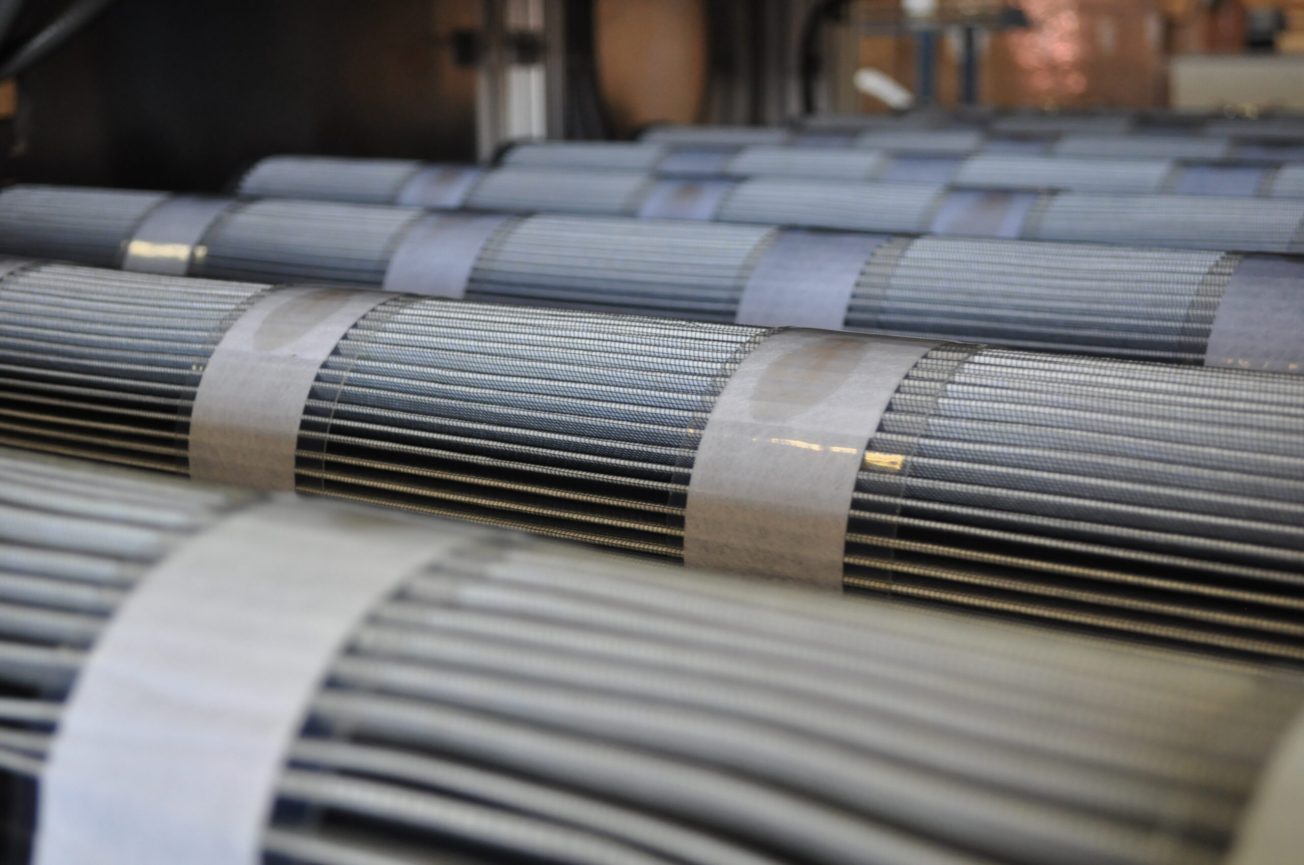 Close-up of multiple filter cartridges arranged in rows, showcasing their metallic structure and protective wrapping, highlighting the process of filter cartridge testing in an industrial setting.