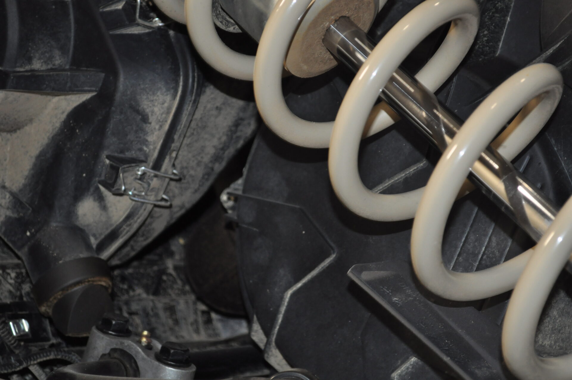 Close-up of a mechanical component of outdoor power equipment, featuring a coil spring and surrounding machinery elements, highlighting the intricate design and functionality of the equipment.