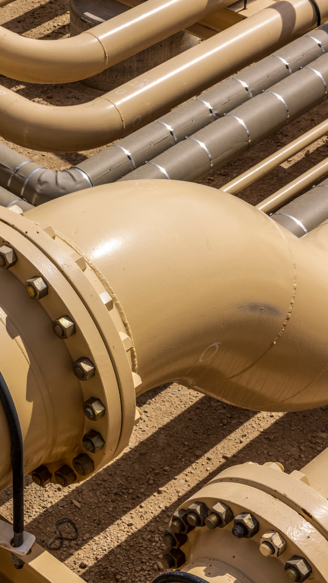 Close-up view of interconnected gas compression pipes and fittings, showcasing a network of beige pipelines with visible bolts and seals, essential for efficient gas transport and compression systems.
