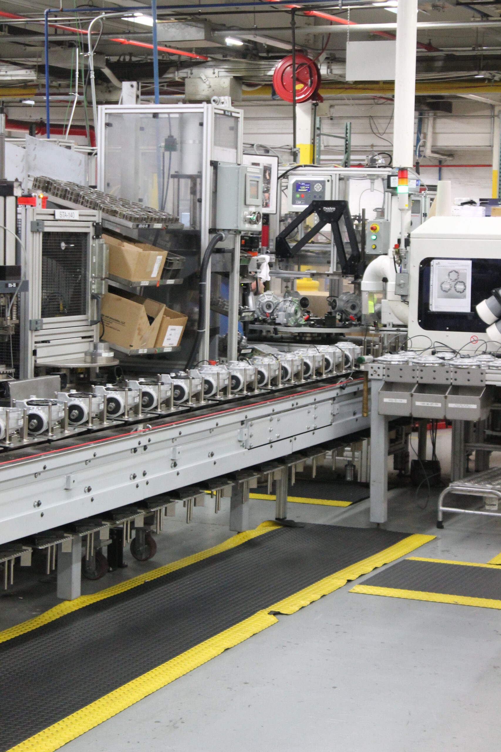 Manufacturing facility featuring a conveyor system with various machines and robotic arms, illustrating advanced automation and production processes in Hilliard.
