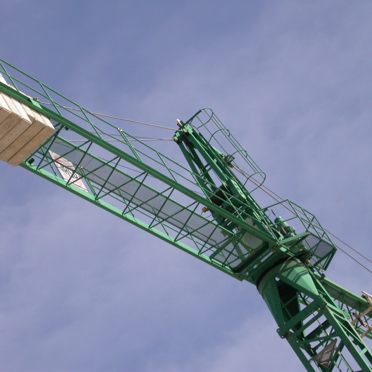 Green construction crane against a blue sky, showcasing its lifting capabilities for material handling in construction projects.