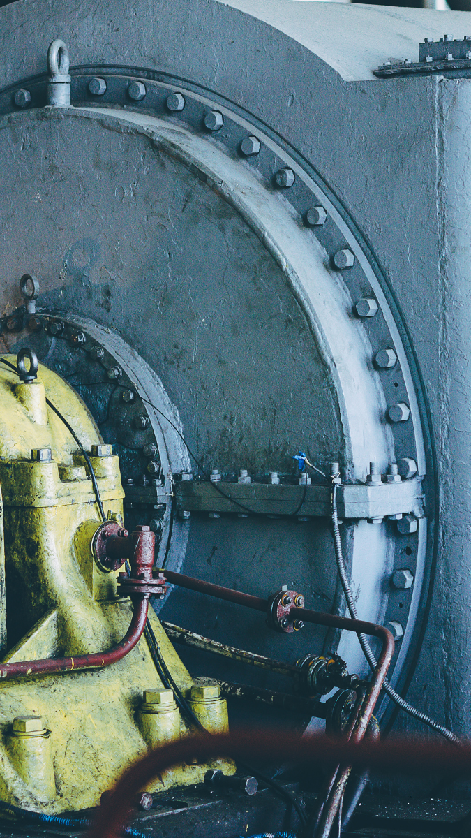 Industrial power generation equipment featuring a yellow turbine and gray casing, showcasing components essential for energy production and efficiency in power plants.