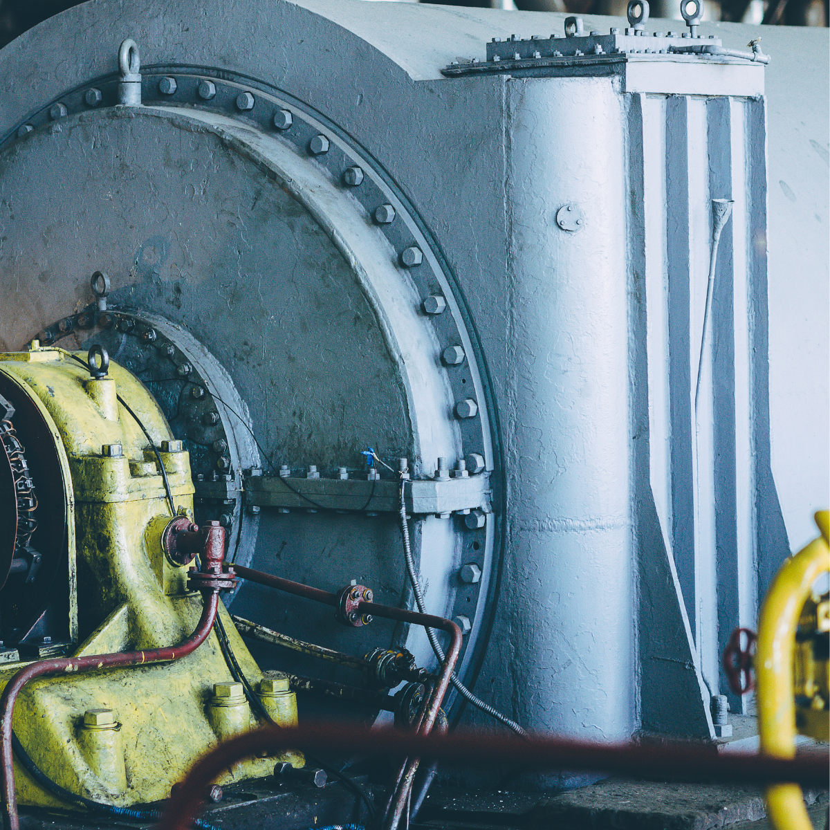 Industrial power generation equipment featuring a yellow turbine and gray casing, showcasing components essential for energy production and efficiency in power plants.