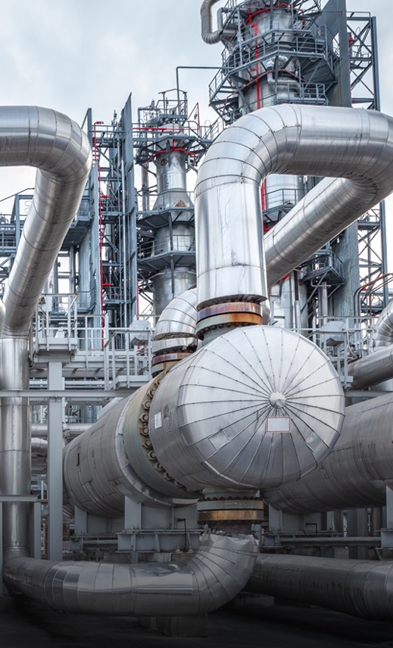 Industrial pipes and equipment at a filtration plant, showcasing stainless steel filter cartridges and complex piping systems used for fluid processing and filtration.