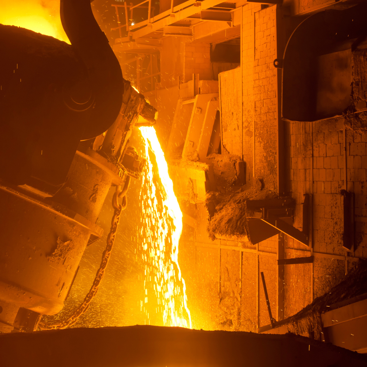 Molten steel being poured from a furnace in a steel manufacturing facility, showcasing the intense heat and industrial processes involved in steel production.