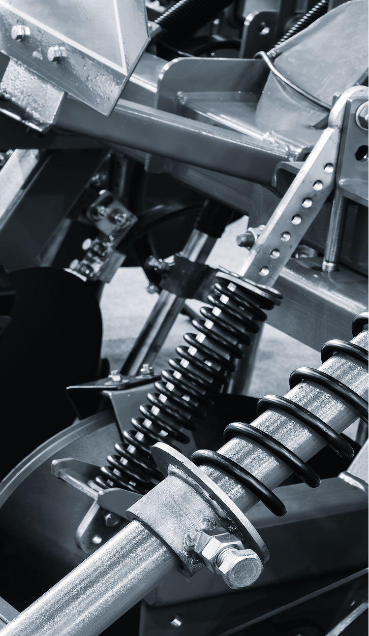 Close-up of heavy machinery components showcasing metal springs, hydraulic systems, and structural elements, highlighting the engineering and design of modern industrial equipment.